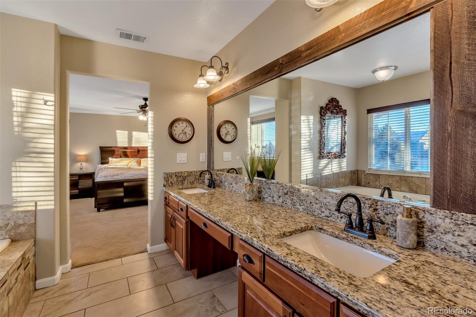 10735 Wynspire Road Highlands Ranch, CO 80130 - Photo 27 of 40 a en suite bathroom with a granite countertop sink and a large mirror