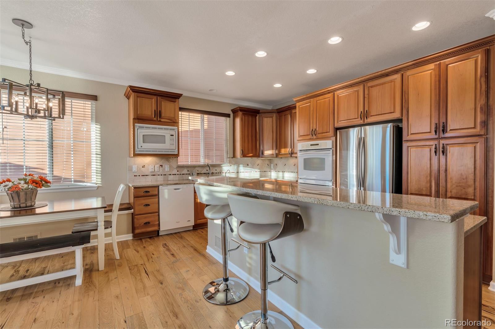 10735 Wynspire Road Highlands Ranch, CO 80130 - Photo 7 of 40 a kitchen with stainless steel appliances granite countertop a refrigerator a stove a sink dishwasher and a stove with wooden floor
