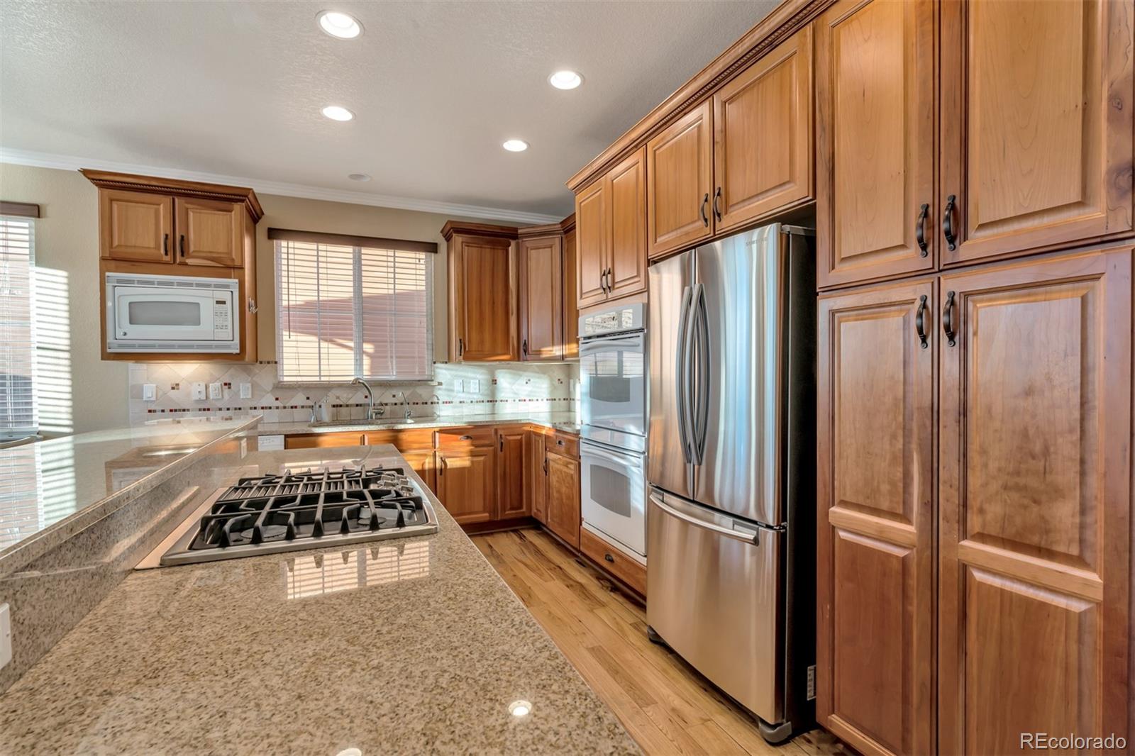 10735 Wynspire Road Highlands Ranch, CO 80130 - Photo 8 of 40 a kitchen with stainless steel appliances a refrigerator a sink a stove and cabinets