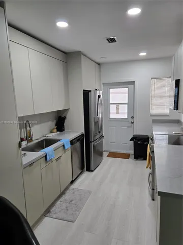 a kitchen with stainless steel appliances a sink a stove a refrigerator and cabinets