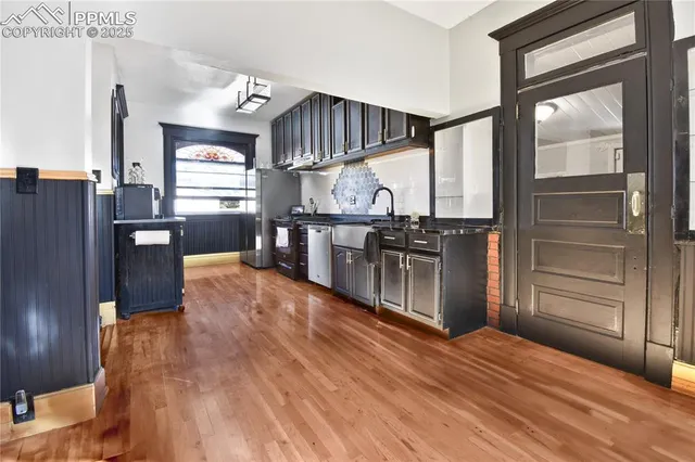a kitchen with stainless steel appliances wooden floor sink and wooden cabinets