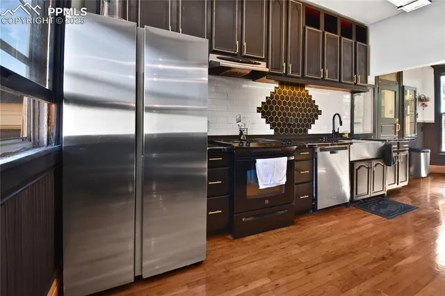 a kitchen with stainless steel appliances granite countertop a refrigerator a stove and a sink with wooden cabinets