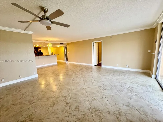 a view of a livingroom with a chandelier fan and a kitchen view