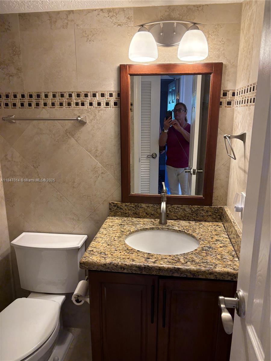 3100 West Rolling Hills Circle, Unit 407 Davie, FL 33328 - Photo 23 of 29 a bathroom with a granite countertop sink and a mirror