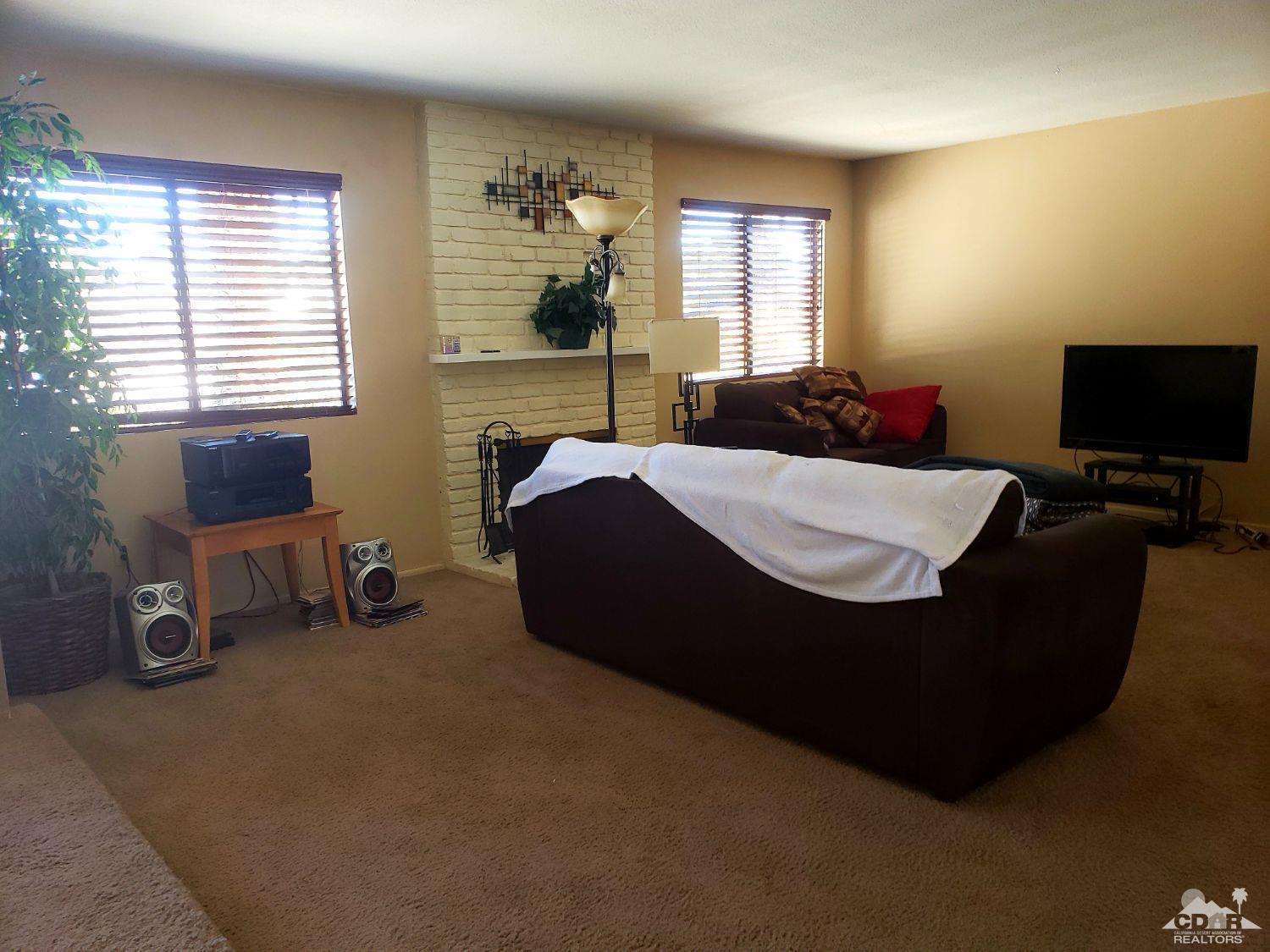 36883 Palmdale Road Rancho Mirage, CA 92270 - Photo 3 of 13 a living room with furniture a flat screen tv and windows