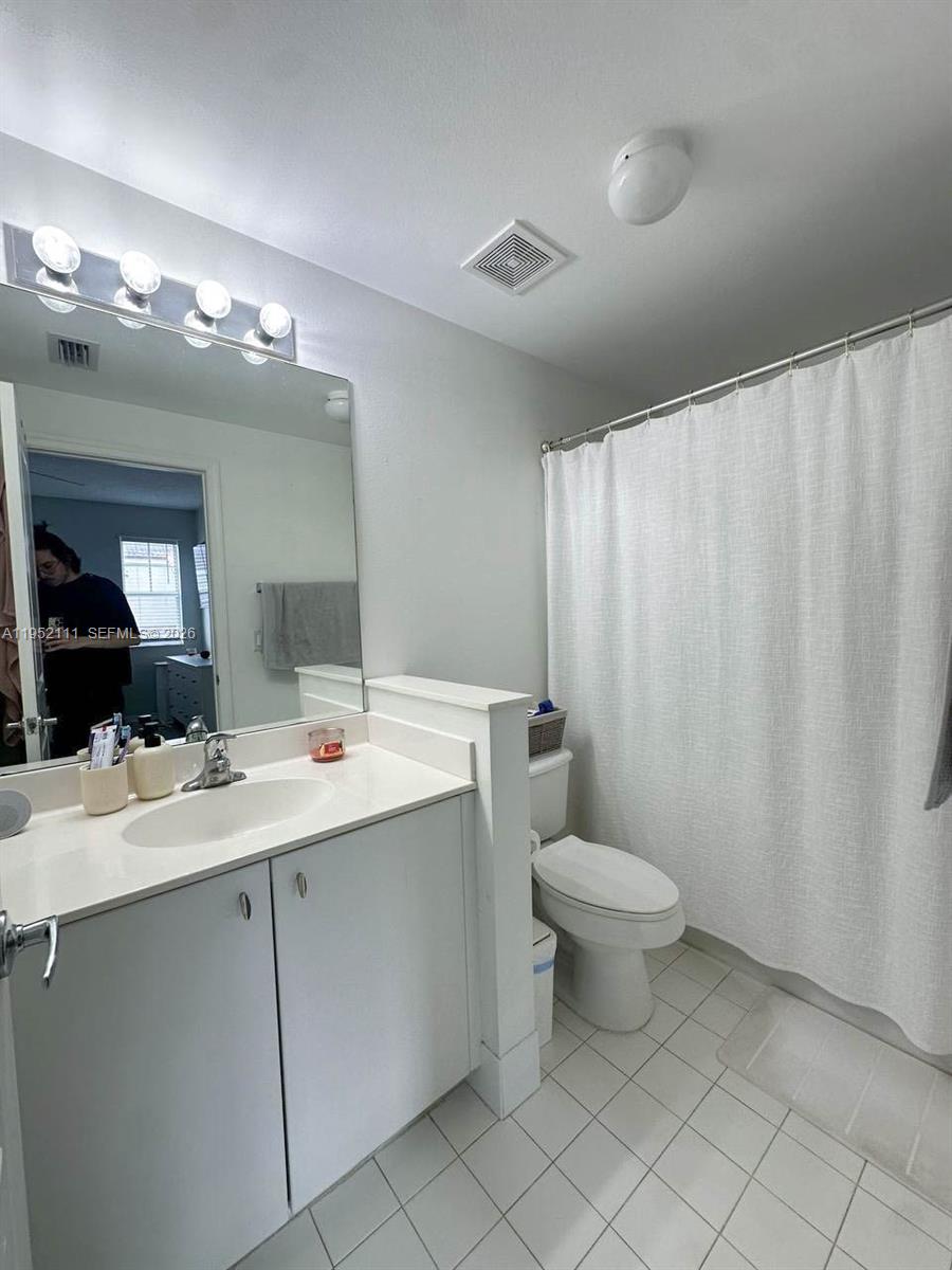 5840 West Sample Road, Unit 305 Coral Springs, FL 33067 - Photo 20 of 38 a bathroom with a double vanity sink toilet and a mirror