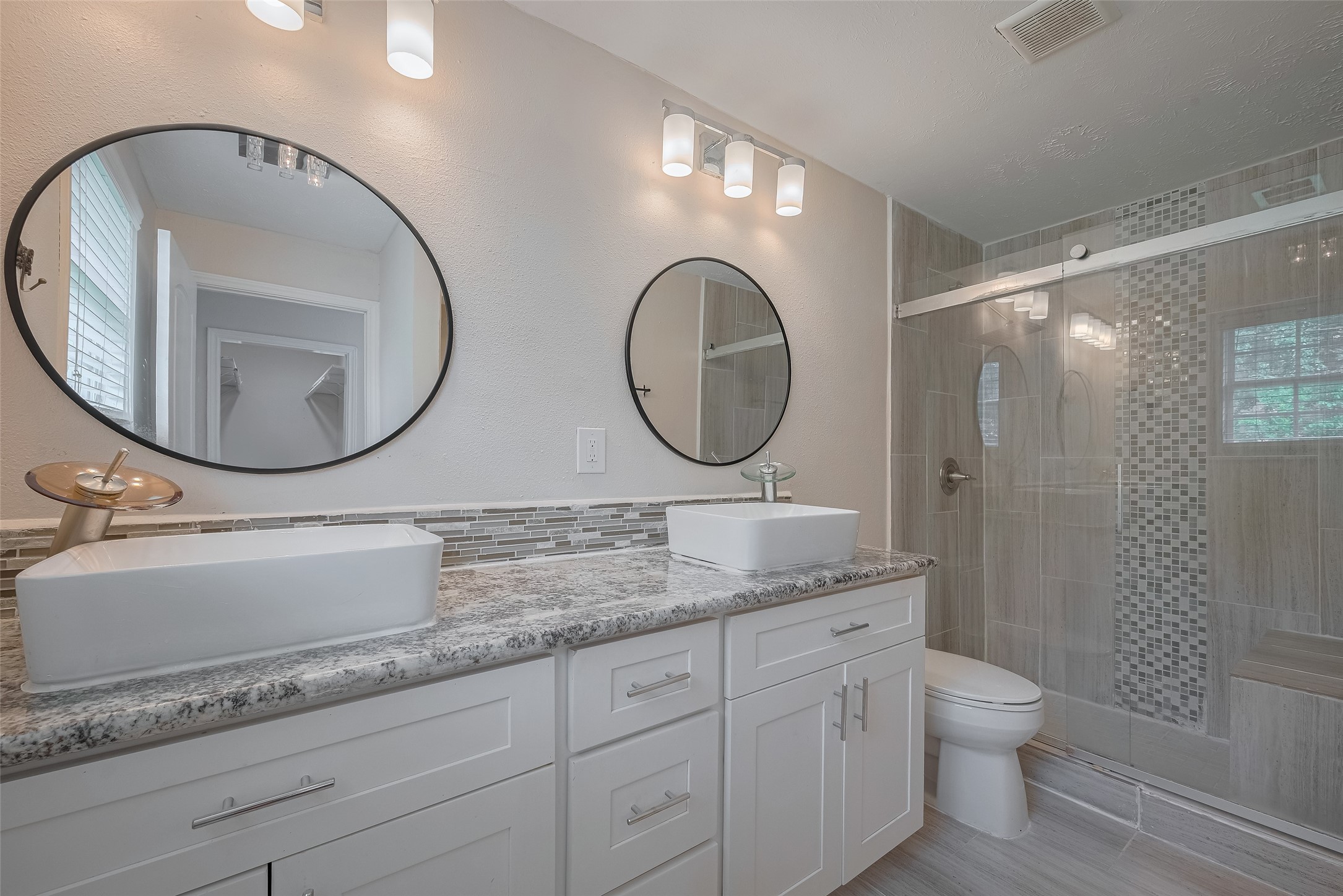 3930 Daphne Street Houston, TX 77021 - Photo 35 of 44 A dual sink vanity, twin mirrors, and modern fixtures frame a stylish bathroom that centers around a glass-enclosed shower—balanced and bright.