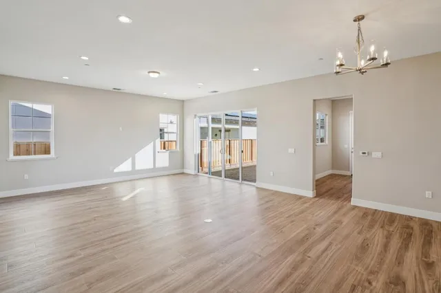 a view of an empty room with window and wooden floor