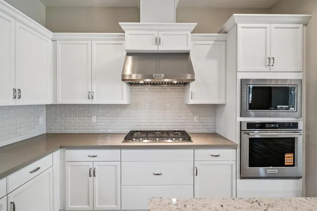 a kitchen with white cabinets and appliances