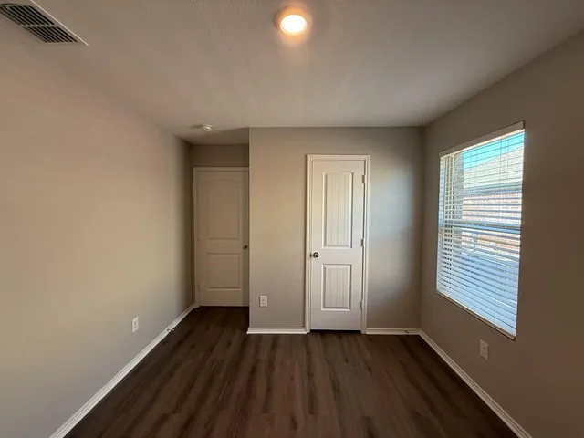 a view of an empty room with wooden floor and a window