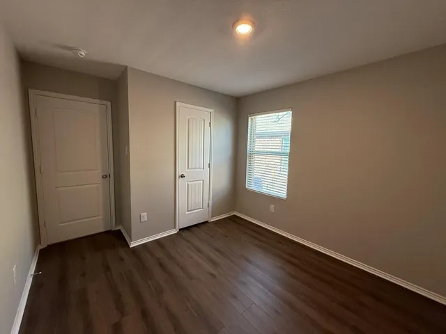 an empty room with wooden floor and windows
