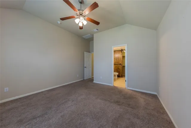 an empty room with chandelier fan and windows