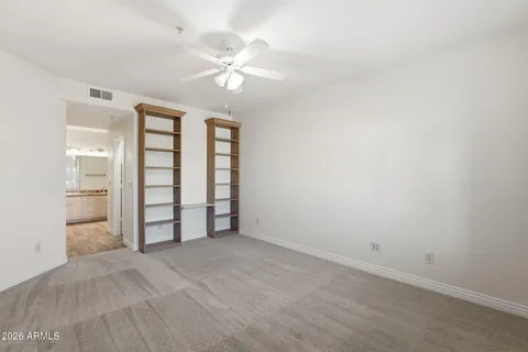 an empty room with windows and fan