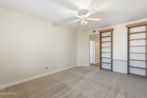 an empty room with windows and fan