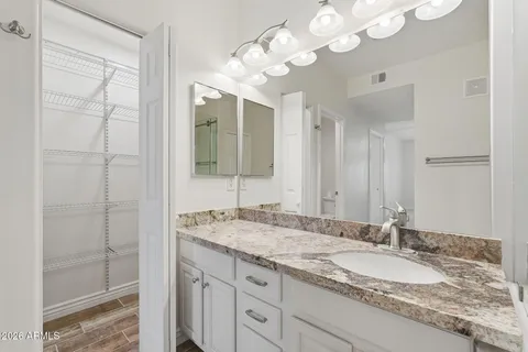 a bathroom with a granite countertop sink a mirror and a shower