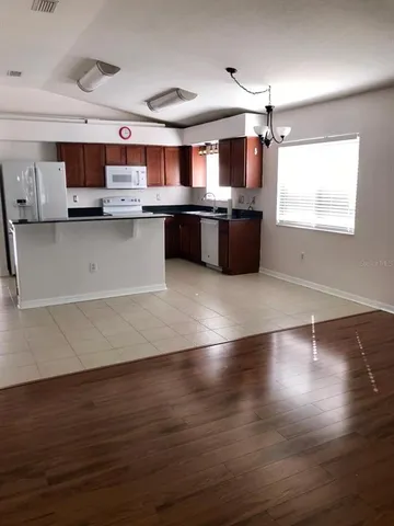 a large kitchen with stainless steel appliances wooden floors and view living room
