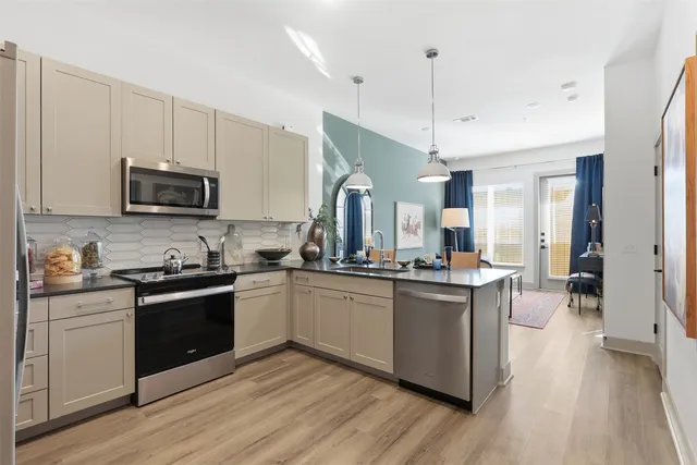 a kitchen with granite countertop a stove top oven a sink dishwasher and a refrigerator