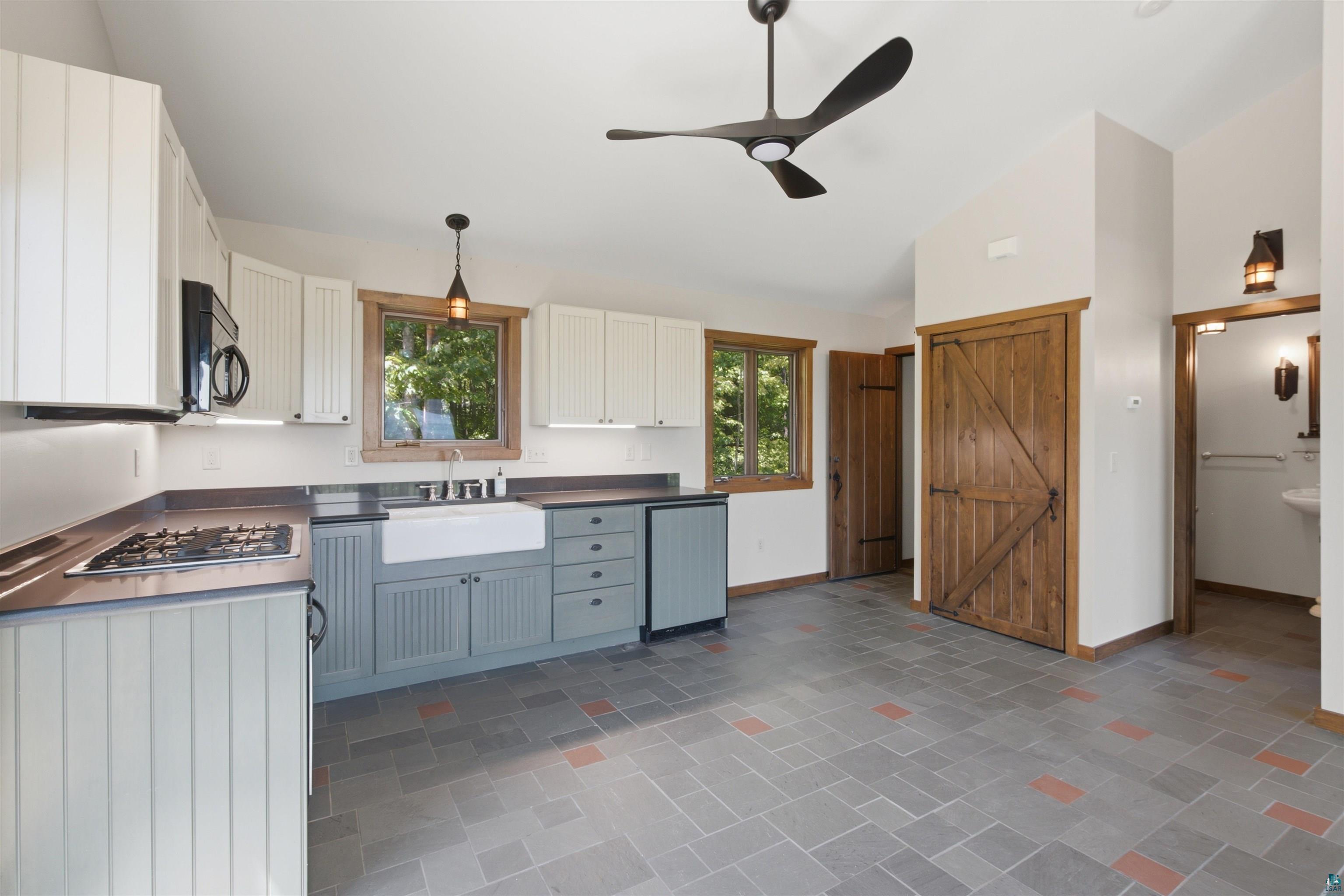 86270 Meyers-Olson Road Bayfield, WI 54814 - Photo 14 of 33 Vaulted ceiling kitchen featuring a black ceiling fan, wood-frame windows, and a farmhouse sink