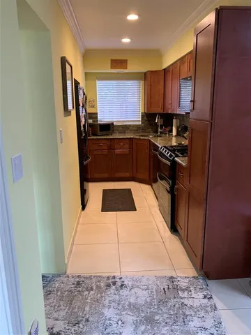 a kitchen with kitchen island granite countertop a refrigerator a sink and wooden cabinets