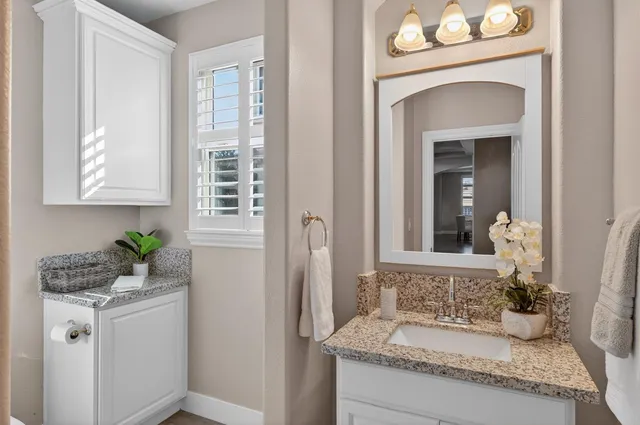 a bathroom with a granite countertop sink and a mirror