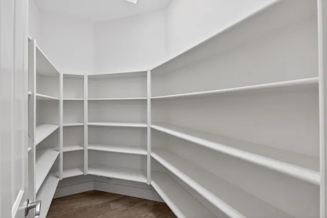 an empty room with wooden floor chandelier fan and windows