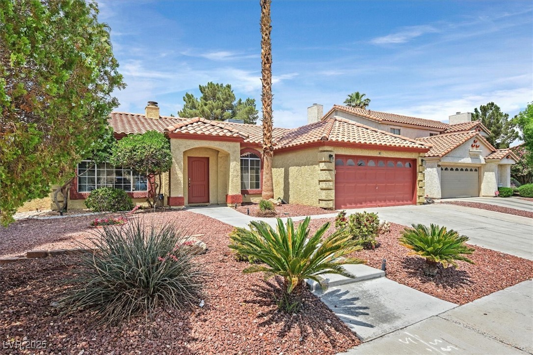 Mediterranean / spanish-style house featuring a tiled roof, a chimney, stucco siding, and a garage