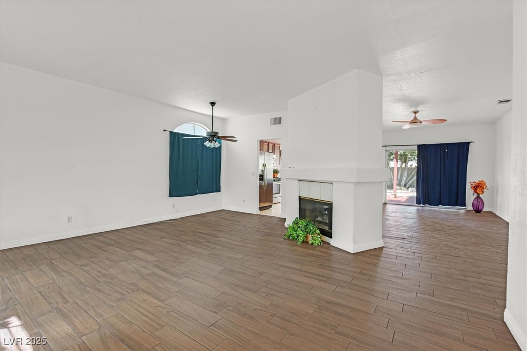 731 Rising Star Drive Henderson, NV 89014 - Photo 4 of 25 Unfurnished living room with ceiling fan, wood finished floors, and a tile fireplace