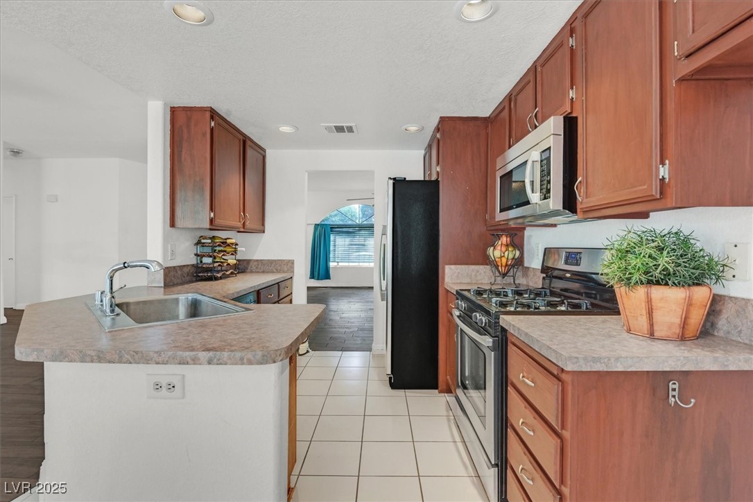 731 Rising Star Drive Henderson, NV 89014 - Photo 9 of 25 Kitchen with stainless steel appliances, a sink, a peninsula, light tile patterned floors, and recessed lighting