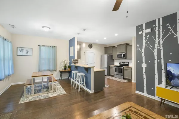 a living room with stainless steel appliances kitchen island granite countertop furniture and a wooden floor