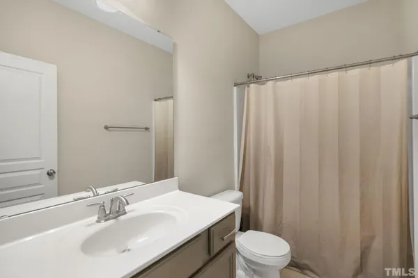 a bathroom with a sink a toilet a mirror and shower curtain