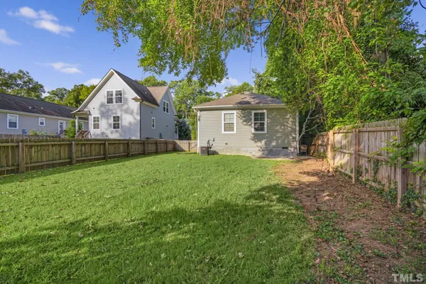 a view of a house with a yard and a large tree