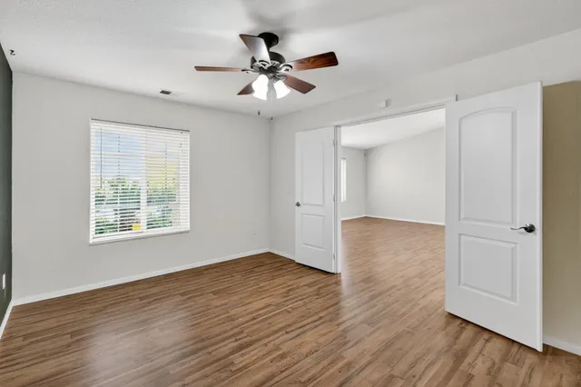 a view of an empty room with wooden floor and a window