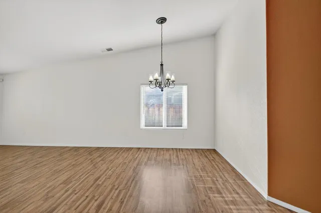 a view of a room with wooden floor ceiling fan and window