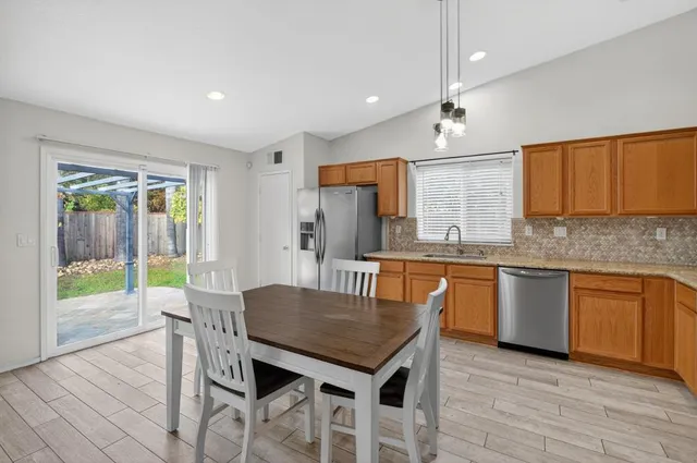 a kitchen with granite countertop kitchen island stainless steel appliances a dining table and chairs