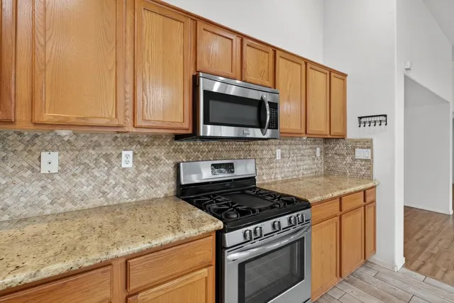 a kitchen with granite countertop a stove top oven microwave and cabinets