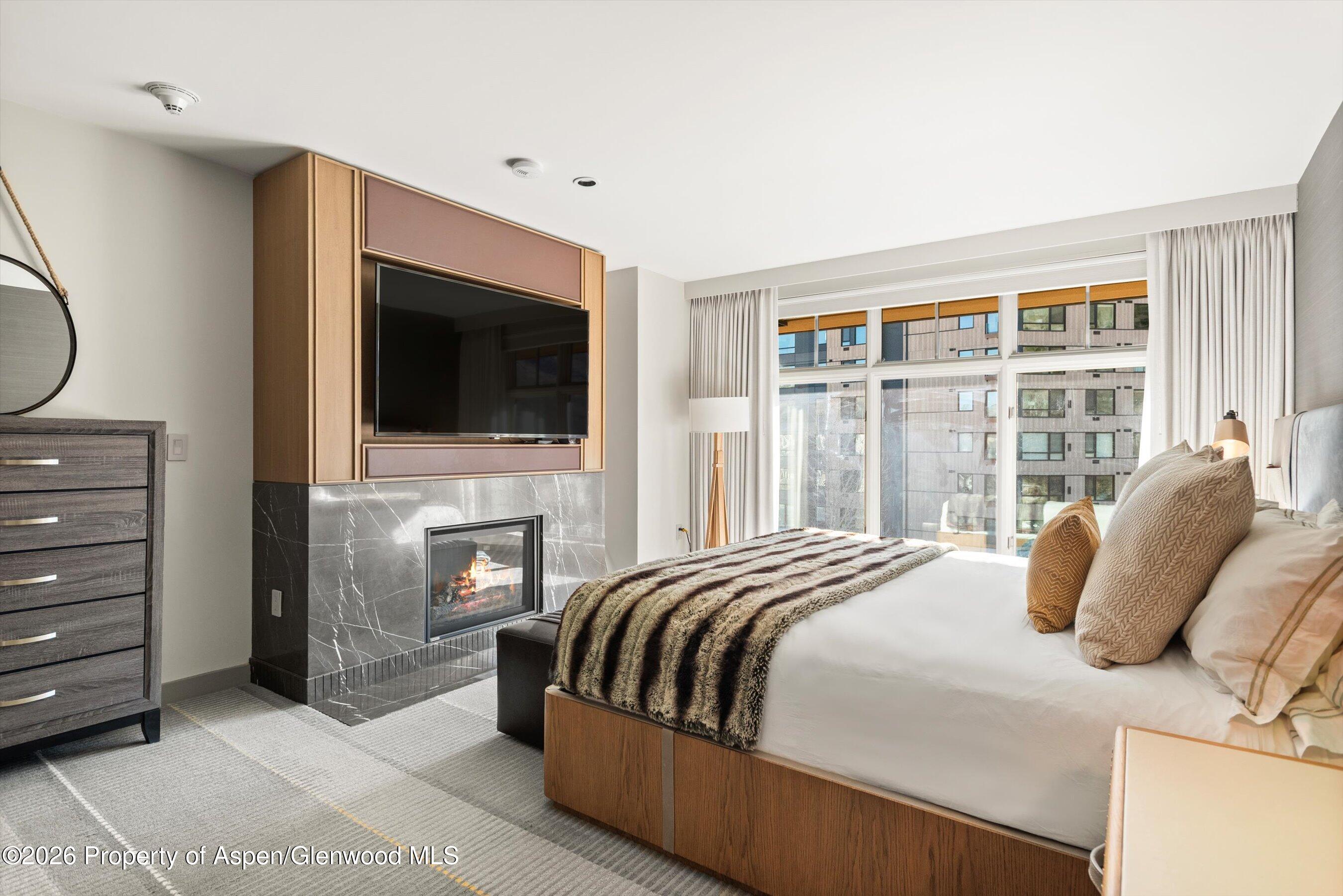 130 Wood Road, Unit 701/801 Snowmass Village, CO 81615 - Photo 30 of 41 a bedroom with a bed a flat screen tv and a fireplace