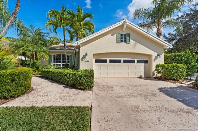 a front view of a house with a yard and potted plants