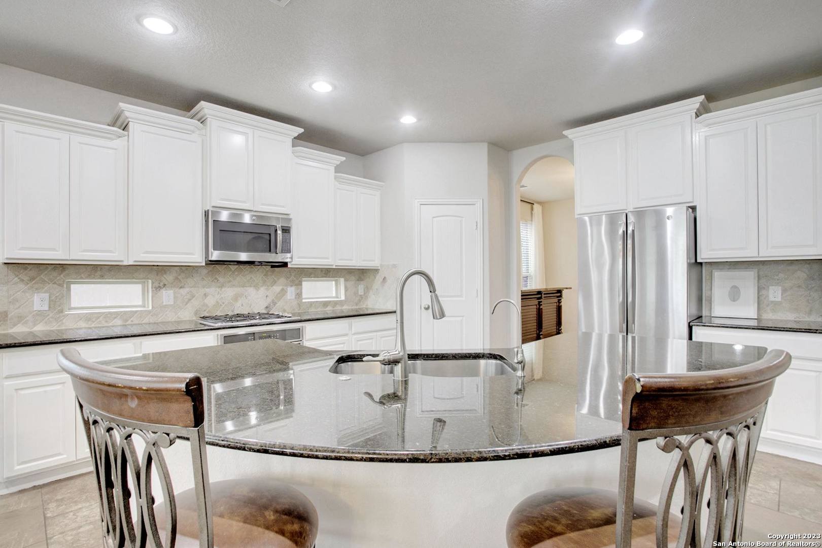 a kitchen with kitchen island a sink white cabinets and stainless steel appliances