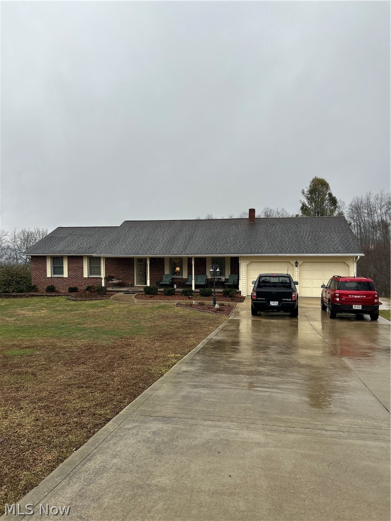 Ranch-style house featuring concrete driveway, a porch, roof with shingles, and an attached garage