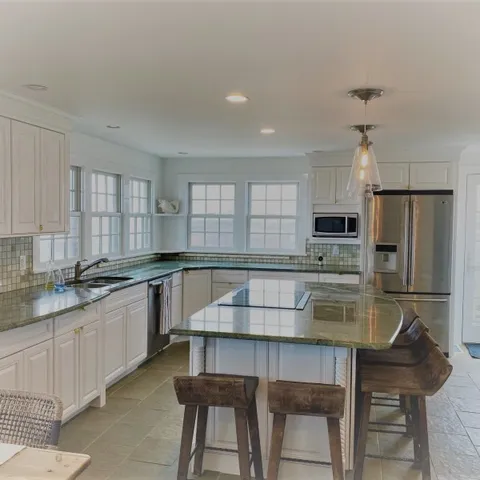 a kitchen with kitchen island granite countertop a table chairs sink and microwave