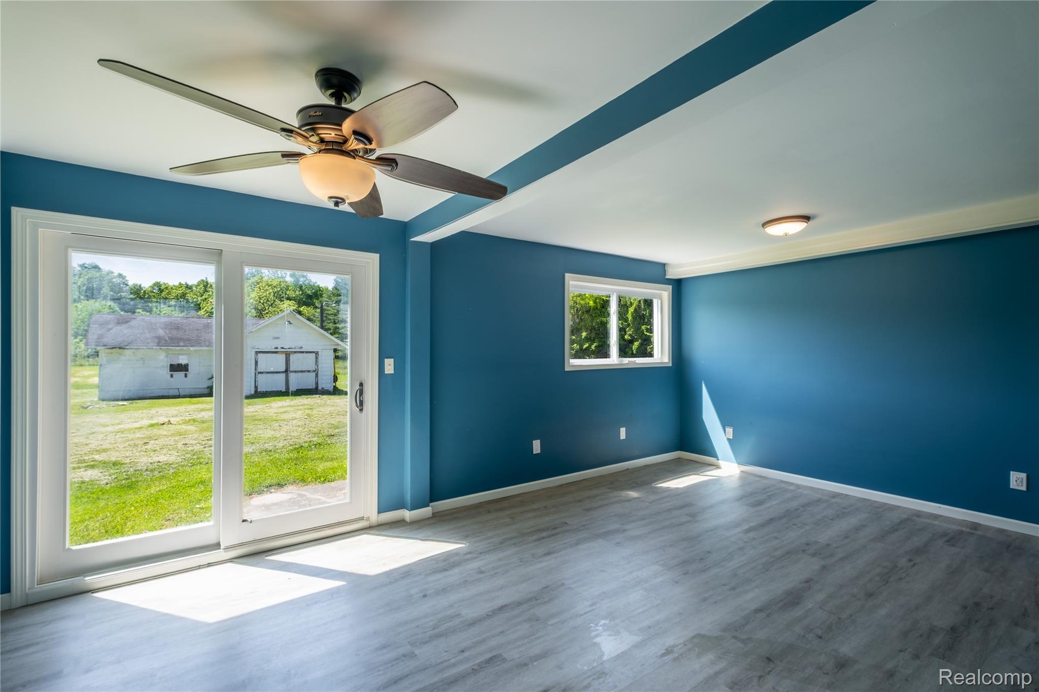 12238 Jennings Road Linden, MI 48451 - Photo 15 of 33 Spacious room featuring wood-finish flooring, a ceiling fan with integrated lighting, and vibrant blue walls