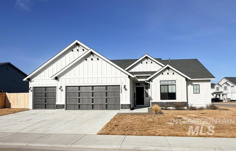 Modern farmhouse style home featuring board and batten siding, stone siding, concrete driveway, and a garage
