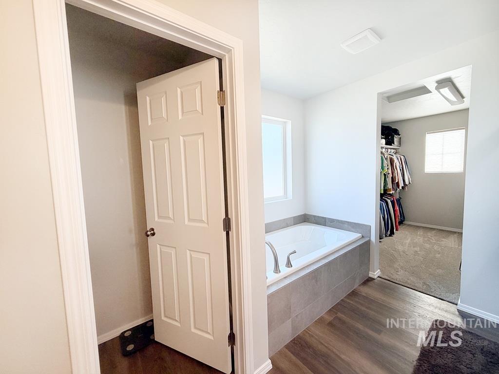 13694 Oliver Street Caldwell, ID 83607 - Photo 23 of 28 Bathroom featuring a bath, dark wood-style flooring, and a spacious closet