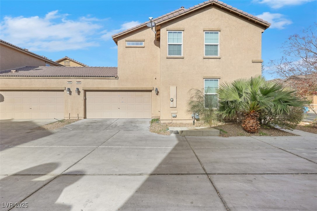 View of front of property with stucco siding, driveway, and a garage