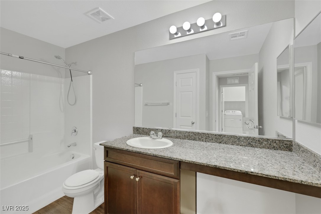 4549 Lime Straight Drive Las Vegas, NV 89115 - Photo 14 of 21 Bathroom featuring vanity, bathtub / shower combination, dark wood-type flooring, and washer / dryer