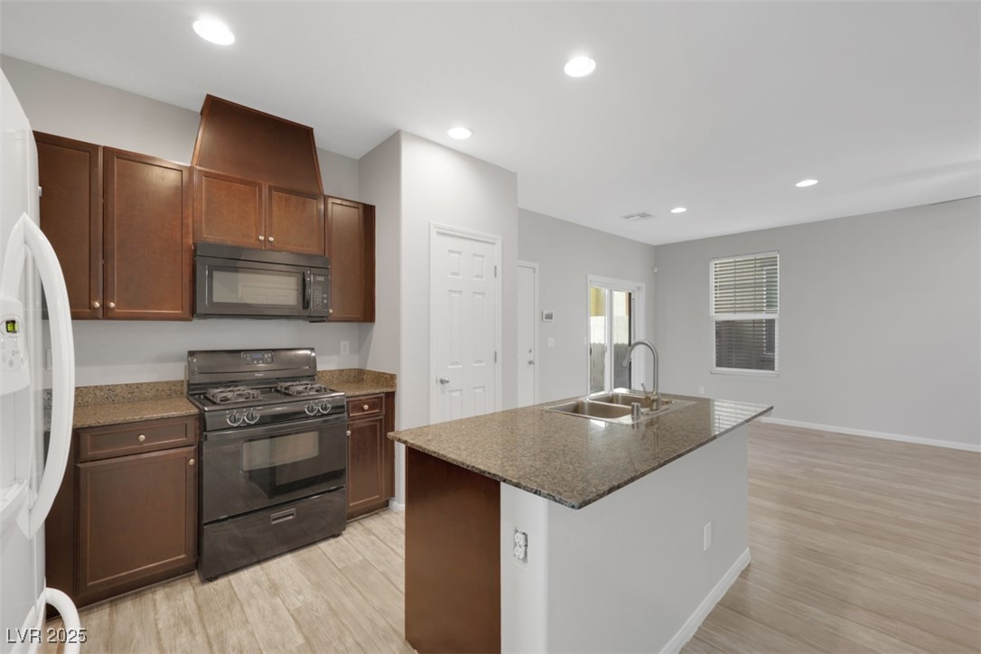 4549 Lime Straight Drive Las Vegas, NV 89115 - Photo 7 of 21 Kitchen with black appliances, recessed lighting, light wood-type flooring, an island with sink, and dark stone countertops