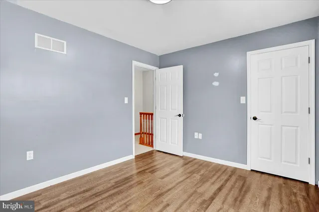 a view of an empty room with wooden floor and closet