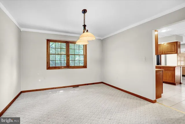 an empty room with chandelier fan and windows