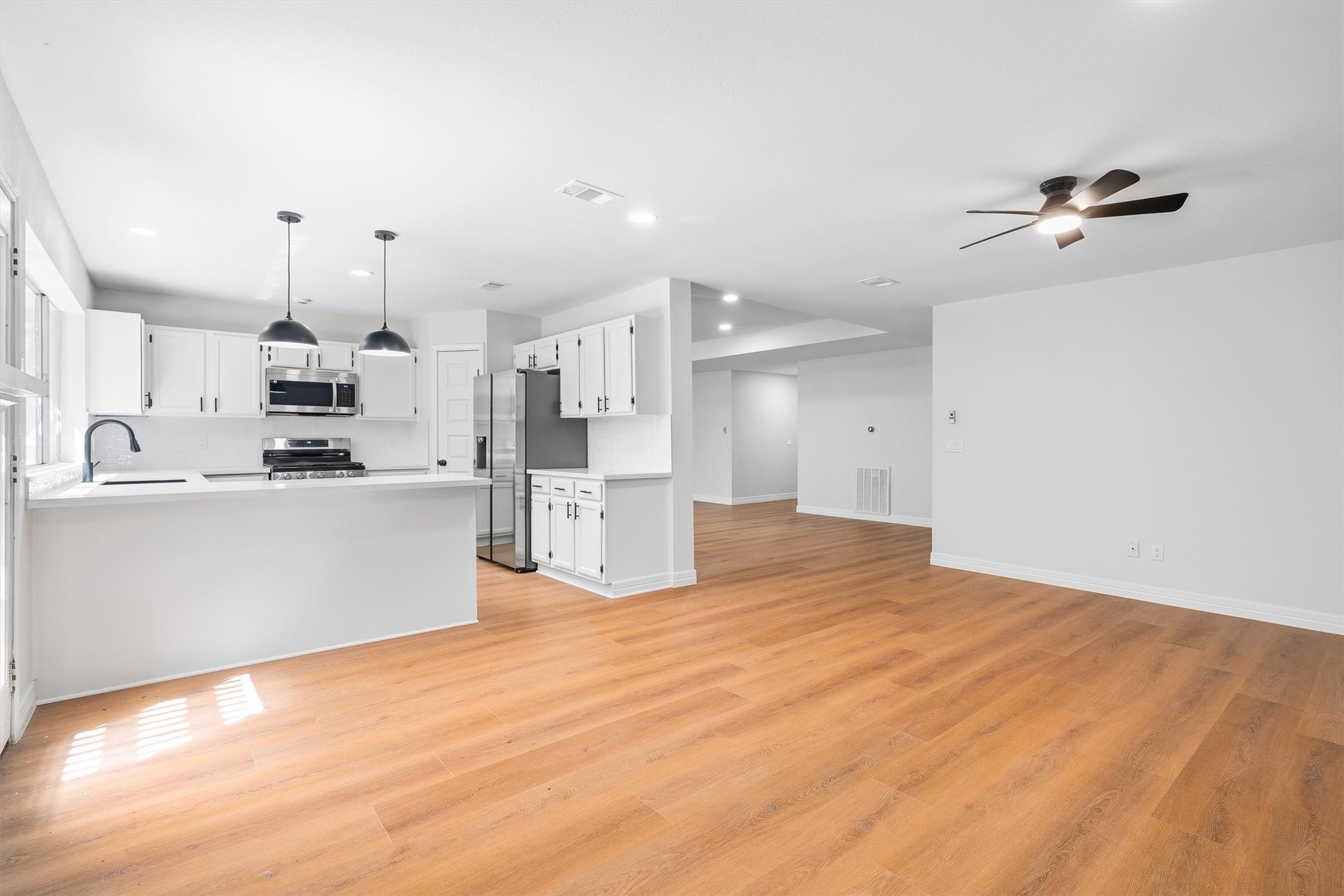 3 Still Corner Place Spring, TX 77381 - Photo 8 of 34 Turning toward the kitchen, crisp white cabinetry, gorgeous quartz countertops, and stainless appliances pop against the warm flooring, and there's even more to love waiting just ahead.
