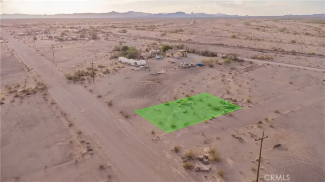 a view of a dry field with mountains in the background